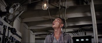 Movie still from “The Sand Pebbles” (1966), directed by Robert Wise – A man standing under an electrical light in a room; Close Up shot, Low angle