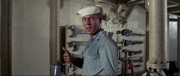 Movie still from “The Sand Pebbles” (1966), directed by Robert Wise – A man wearing a white hat and holding a wrench in his hand; Medium shot, High angle