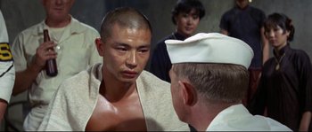 Movie still from “The Sand Pebbles” (1966), directed by Robert Wise – A man with a towel around his neck talks to another man; Close Up shot, Over the shoulder angle