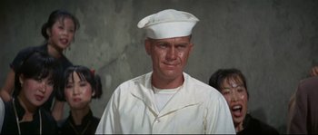Movie still from “The Sand Pebbles” (1966), directed by Robert Wise – A man wearing a white hat and a white shirt; Close Up shot, Low angle