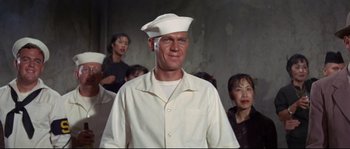 Movie still from “The Sand Pebbles” (1966), directed by Robert Wise – A man wearing a sailor's hat in front of a group of people; Medium shot, Low angle