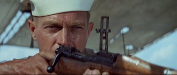 Movie still from “The Sand Pebbles” (1966), directed by Robert Wise – A man in a sailor's hat is holding a rifle; Close Up shot, Low angle