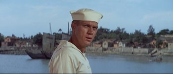 Movie still from “The Sand Pebbles” (1966), directed by Robert Wise – A man wearing a hat standing next to a body of water; Close Up shot, Low angle