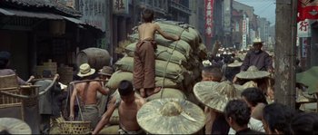 Movie still from “The Sand Pebbles” (1966), directed by Robert Wise – A group of people standing around a pile of bags; Wide shot, High angle