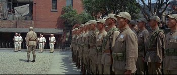 Movie still from “The Sand Pebbles” (1966), directed by Robert Wise – A group of men in uniform standing in front of a brick building; Wide shot, Low angle