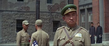 Movie still from “The Sand Pebbles” (1966), directed by Robert Wise – A man in a military uniform standing next to another man; Medium shot, Low angle