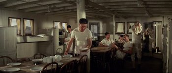 Movie still from “The Sand Pebbles” (1966), directed by Robert Wise – A group of people sitting at a table in a room; Wide shot, Low angle