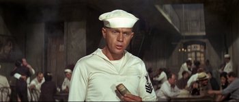 Movie still from “The Sand Pebbles” (1966), directed by Robert Wise – A man in a sailor's uniform holding a roll of money; Medium shot, Low angle