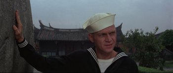Movie still from “The Sand Pebbles” (1966), directed by Robert Wise – A man wearing a sailor's hat in front of an asian building; Close Up shot, Low angle