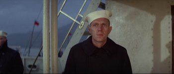 Movie still from “The Sand Pebbles” (1966), directed by Robert Wise – A man wearing a sailor's hat standing in front of a building; Medium shot, Low angle