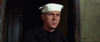 Movie still from “The Sand Pebbles” (1966), directed by Robert Wise – A man wearing a sailor's hat and a black coat; Close Up shot, Low angle