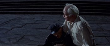 Movie still from “The Sand Pebbles” (1966), directed by Robert Wise – An older man and a young man sitting on the ground; Medium shot, High angle
