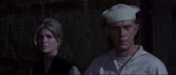 Movie still from “The Sand Pebbles” (1966), directed by Robert Wise – A man and a woman standing next to each other in front of a stone wall; Close Up shot, Low angle