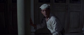 Movie still from “The Sand Pebbles” (1966), directed by Robert Wise – A man in a sailor's uniform standing next to a pillar; Medium shot, Low angle