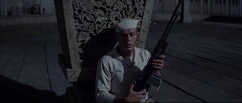 Movie still from “The Sand Pebbles” (1966), directed by Robert Wise – A man holding a rifle while sitting on the ground; Medium shot, High angle