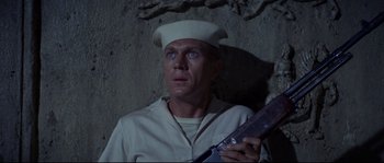 Movie still from “The Sand Pebbles” (1966), directed by Robert Wise – A man in a white shirt and hat holding a knife; Close Up shot, High angle