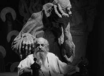 Movie still from “The Scarlet Empress” (1934), directed by Josef von Sternberg – An old man sitting in front of a statue of a demon; Medium shot, Low angle