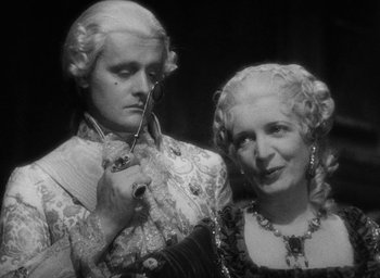 Movie still from “The Scarlet Empress” (1934), directed by Josef von Sternberg – A man and a woman in period clothing holding a pair of scissors; Close Up shot, Over the shoulder angle