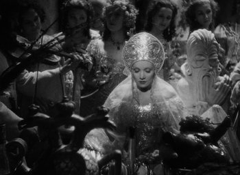 Movie still from “The Scarlet Empress” (1934), directed by Josef von Sternberg – A group of people in a room with a woman in a dress; Medium shot, High angle