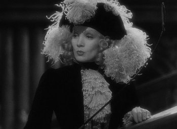 Movie still from “The Scarlet Empress” (1934), directed by Josef von Sternberg – A woman wearing a hat and a black dress; Close Up shot, Over the shoulder angle