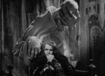 Movie still from “The Scarlet Empress” (1934), directed by Josef von Sternberg – A man sitting in front of a large creature; Medium shot, Low angle