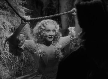 Movie still from “The Scarlet Empress” (1934), directed by Josef von Sternberg – A black - and - white photo of a woman holding a rope; Medium shot, Over the shoulder angle