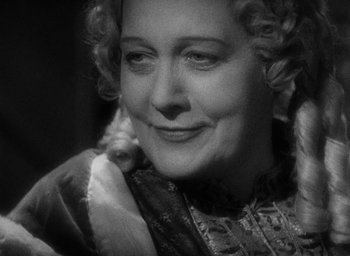 Movie still from “The Scarlet Empress” (1934), directed by Josef von Sternberg – An older woman is smiling for the camera; Close Up shot, High angle