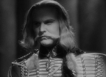 Movie still from “The Scarlet Empress” (1934), directed by Josef von Sternberg – A black and white photo of a man with long hair; Close Up shot, Over the shoulder angle