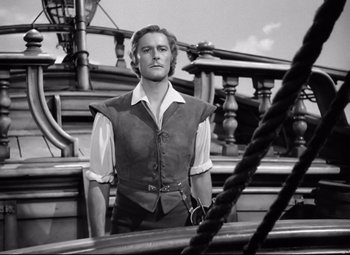 Movie still from “The Sea Hawk” (1940), directed by Michael Curtiz – Black and white photograph of a man standing on a boat; Medium shot, Low angle
