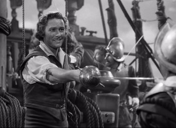 Movie still from “The Sea Hawk” (1940), directed by Michael Curtiz – An old photo of a man holding a sword on a boat; Medium shot, High angle