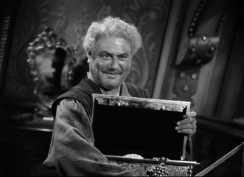 Movie still from “The Sea Hawk” (1940), directed by Michael Curtiz – An older man holding a black box in front of a mirror; Medium shot, Low angle