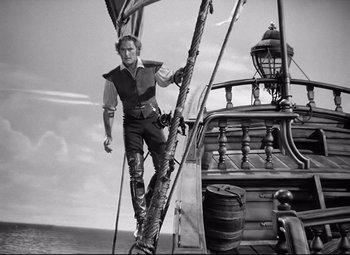 Movie still from “The Sea Hawk” (1940), directed by Michael Curtiz – Black and white photograph of a man standing on a boat; Wide shot, Low angle