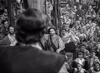 Movie still from “The Sea Hawk” (1940), directed by Michael Curtiz – A crowd of people sitting in a room; Wide shot, High angle