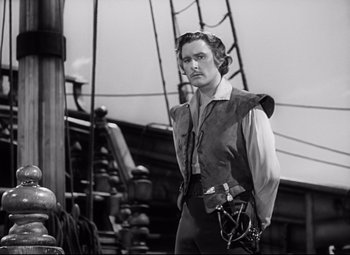 Movie still from “The Sea Hawk” (1940), directed by Michael Curtiz – A man standing on top of a boat in the water; Medium shot, Low angle