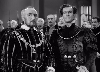 Movie still from “The Sea Hawk” (1940), directed by Michael Curtiz – A black and white photo of two men in medieval garb; Medium shot, Over the shoulder angle