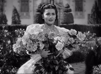 Movie still from “The Sea Hawk” (1940), directed by Michael Curtiz – An old photo of a woman holding a bouquet of flowers; Medium shot, High angle