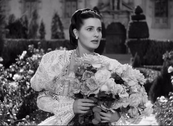 Movie still from “The Sea Hawk” (1940), directed by Michael Curtiz – A black and white photo of a woman holding a bouquet of flowers; Close Up shot, Low angle