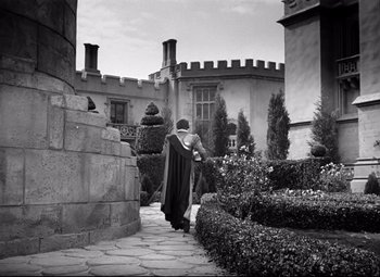 Movie still from “The Sea Hawk” (1940), directed by Michael Curtiz – A man in a black robe walking down a path; Extreme Wide shot, High angle