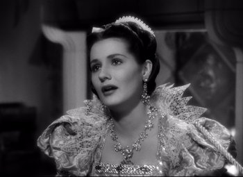 Movie still from “The Sea Hawk” (1940), directed by Michael Curtiz – A woman wearing a dress and a tiara; Close Up shot, Over the shoulder angle