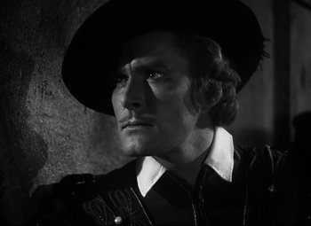 Movie still from “The Sea Hawk” (1940), directed by Michael Curtiz – A black and white photo of a man wearing a cowboy hat; Close Up shot, Low angle