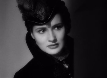 Movie still from “The Sea Hawk” (1940), directed by Michael Curtiz – A woman in a black coat with a hat on her head; Close Up shot, Low angle