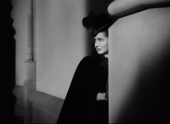 Movie still from “The Sea Hawk” (1940), directed by Michael Curtiz – A black and white photo of a woman wearing a hat; Close Up shot, Over the shoulder angle