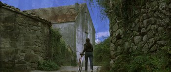 Movie still from “The Sea Inside” (2004), directed by Alejandro Amenábar – A person standing next to a bicycle in front of a house; Extreme Wide shot, Low angle