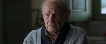 Movie still from “The Sea Inside” (2004), directed by Alejandro Amenábar – An old man with a gray beard looking at the camera; Close Up shot, Over the shoulder angle