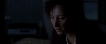 Movie still from “The Sea Inside” (2004), directed by Alejandro Amenábar – An older woman sitting in a dark room looking sad; Close Up shot, Over the shoulder angle
