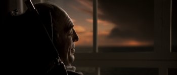 Movie still from “The Sea Inside” (2004), directed by Alejandro Amenábar – An older man looking out a window at the sunset; Close Up shot, Over the shoulder angle