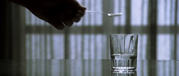 Movie still from “The Sea Inside” (2004), directed by Alejandro Amenábar – A person holding a spoon over a glass of water; Extreme Close Up shot, High angle
