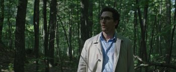 Movie still from “The Sea of Trees” (2015), directed by Gus Van Sant – A man wearing glasses and a white jacket standing in the woods; Medium shot, Low angle