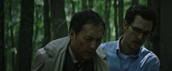 Movie still from “The Sea of Trees” (2015), directed by Gus Van Sant – A man in a trench coat with a knife in his mouth; Close Up shot, Low angle