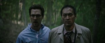Movie still from “The Sea of Trees” (2015), directed by Gus Van Sant – A couple of men standing next to each other in the woods; Medium shot, Low angle